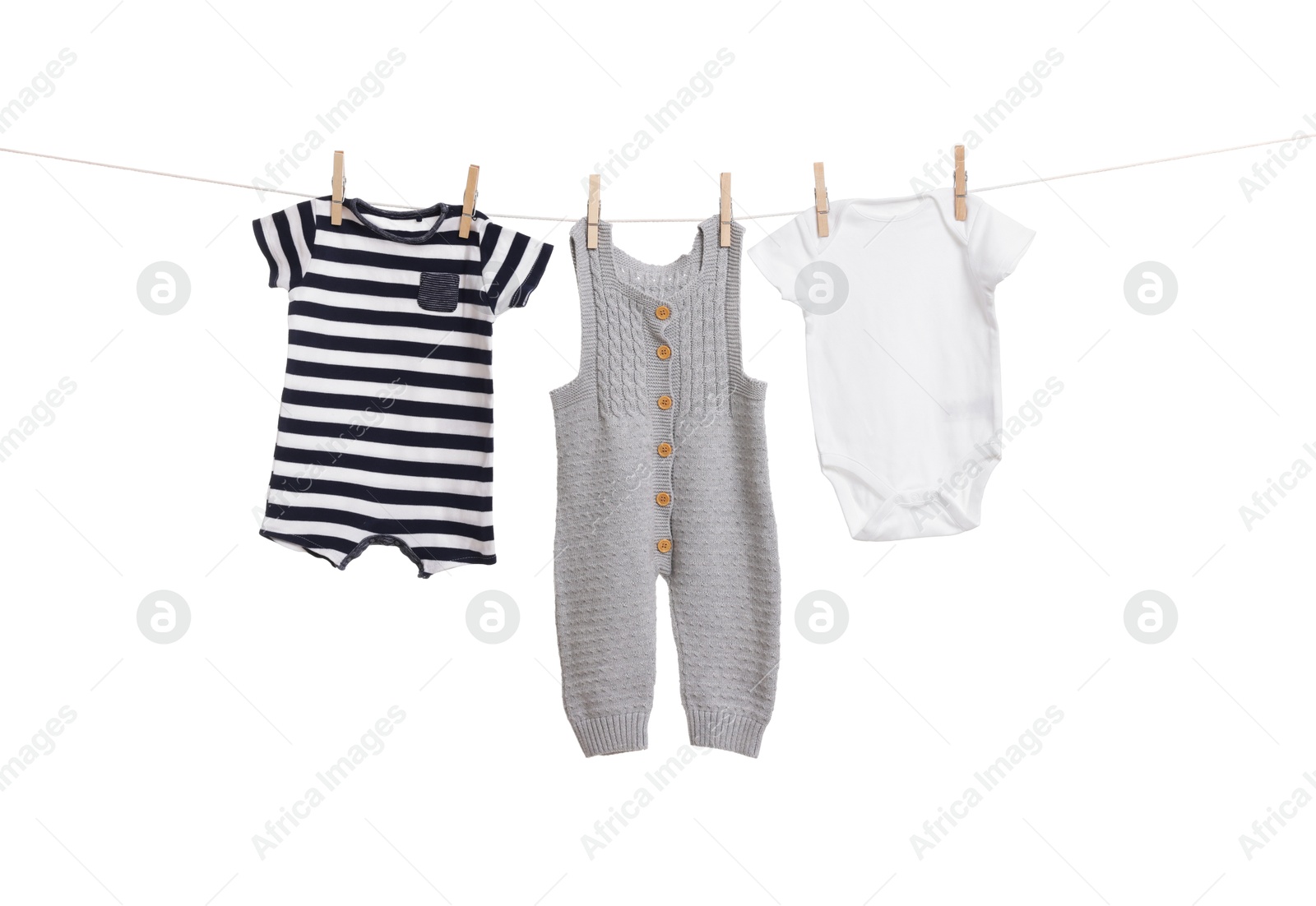 Photo of Different baby clothes drying on laundry line against white background