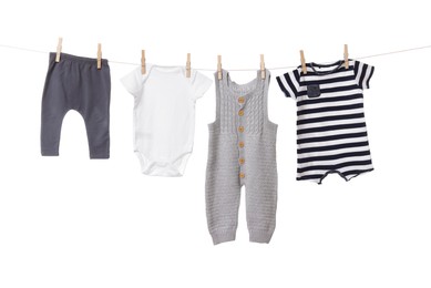 Photo of Different baby clothes drying on laundry line against white background