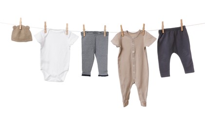 Different baby clothes drying on laundry line against white background