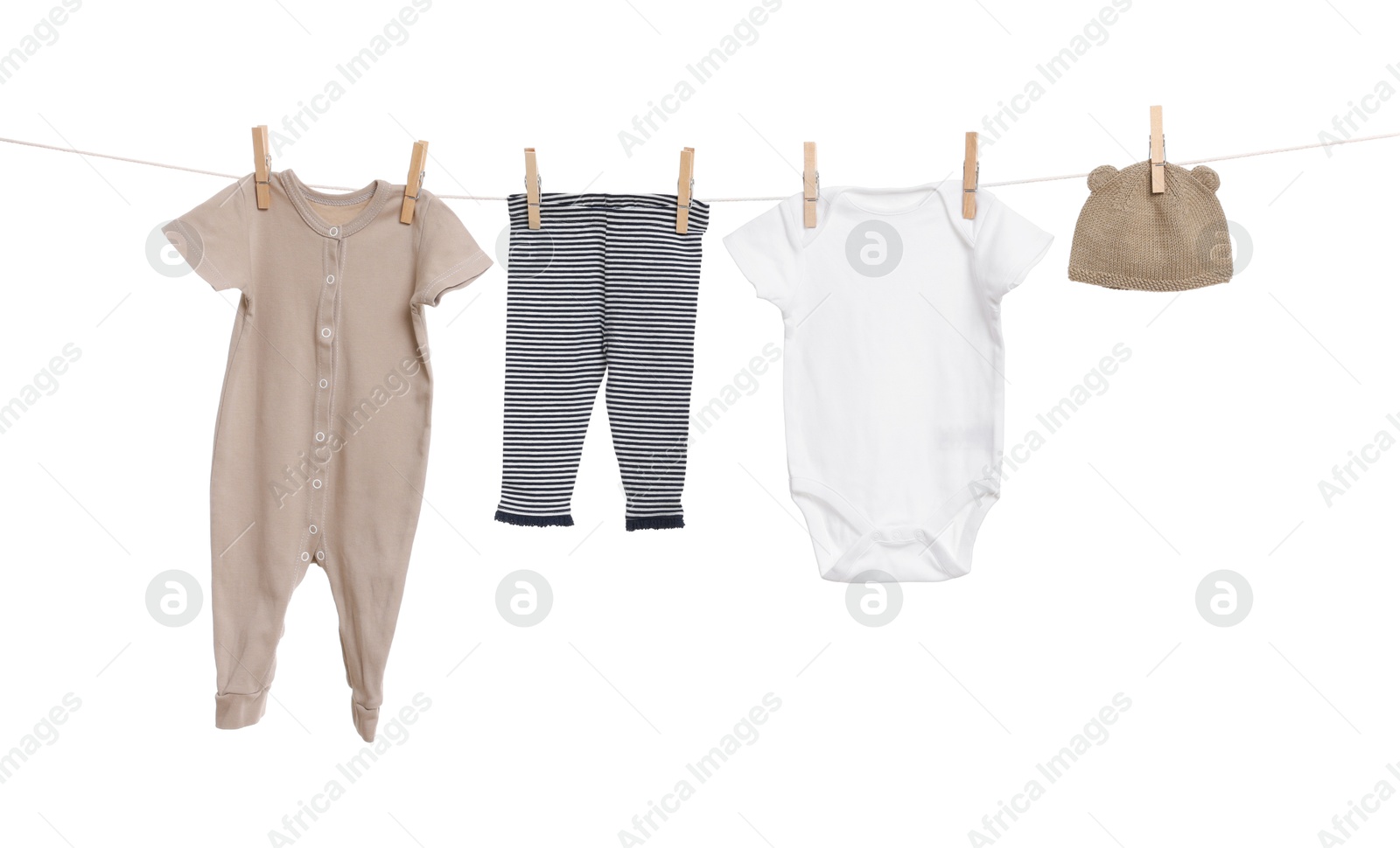 Photo of Different baby clothes drying on laundry line against white background