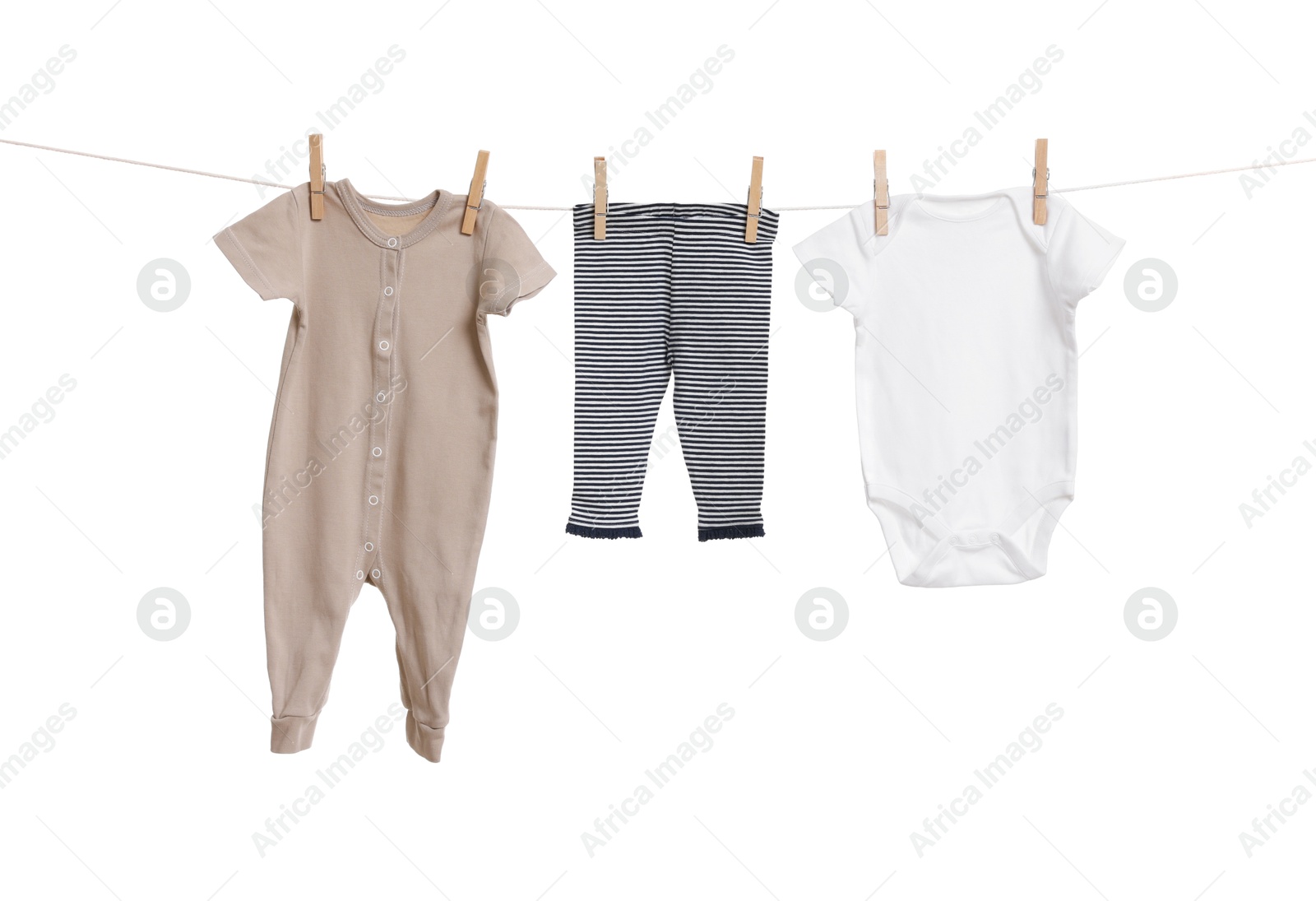 Photo of Different baby clothes drying on laundry line against white background