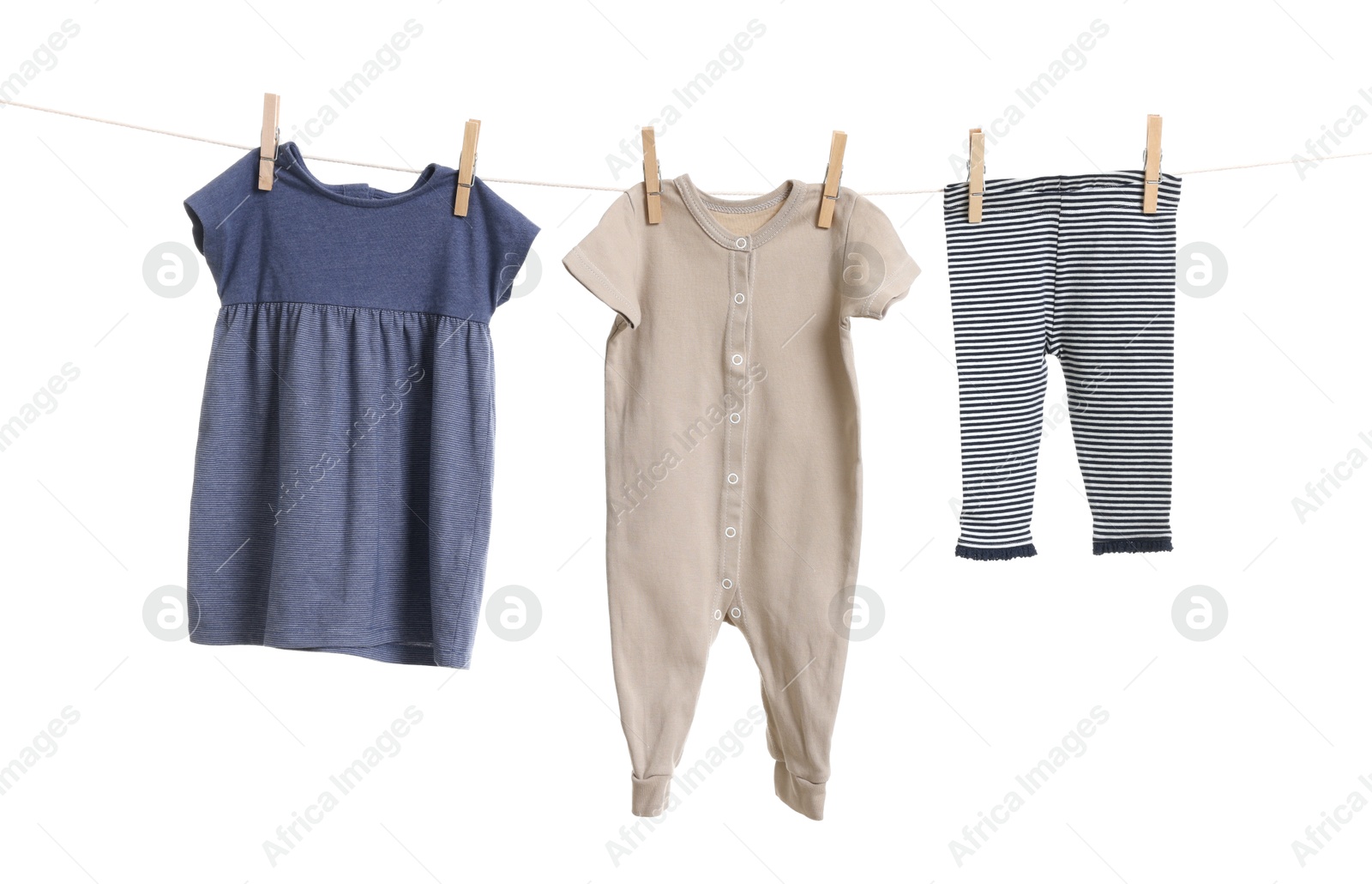 Photo of Different baby clothes drying on laundry line against white background