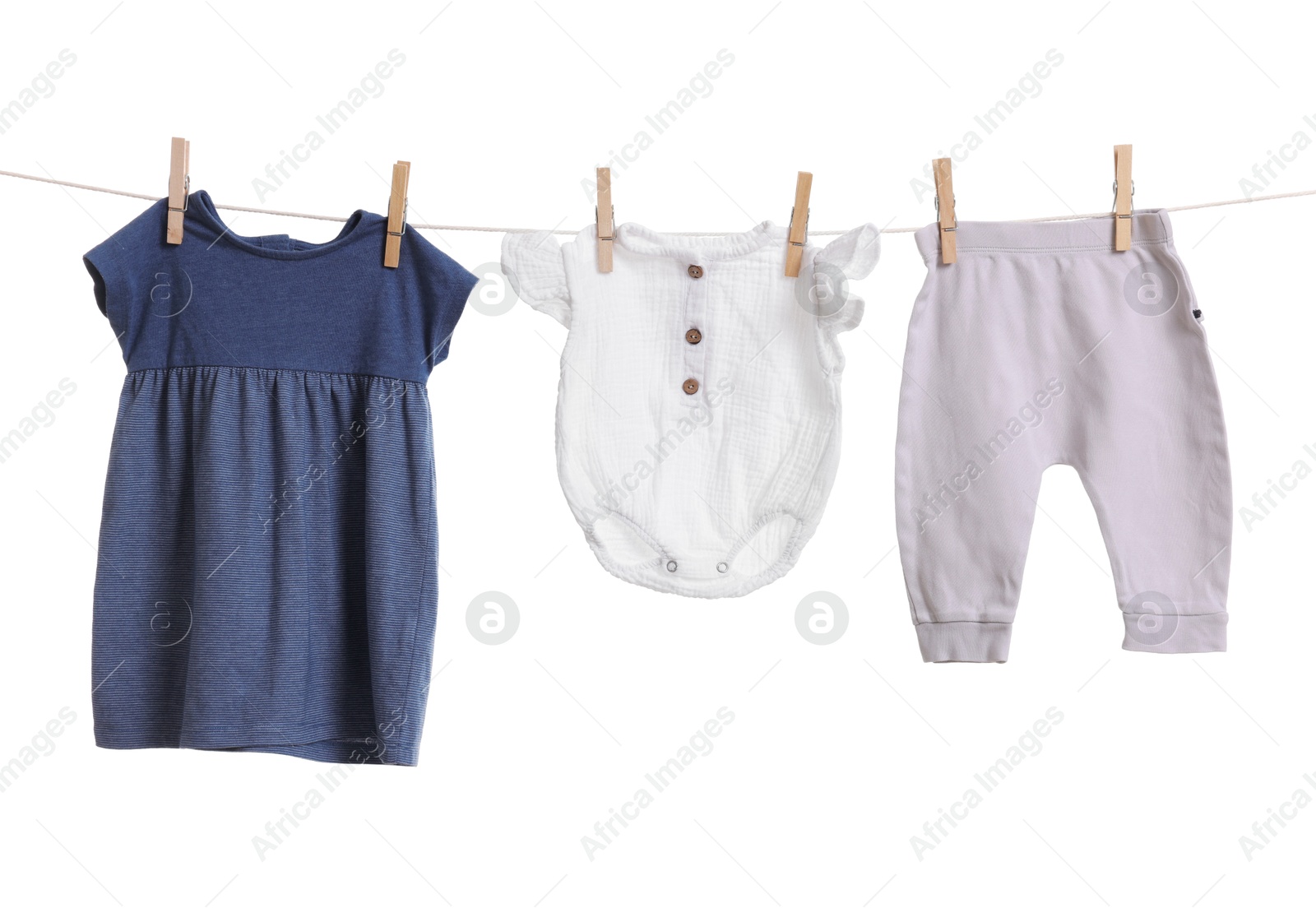 Photo of Different baby clothes drying on laundry line against white background