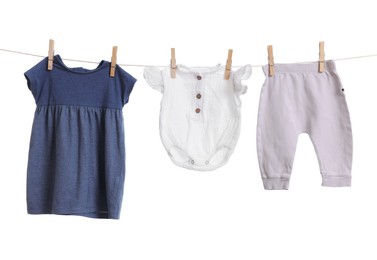 Photo of Different baby clothes drying on laundry line against white background