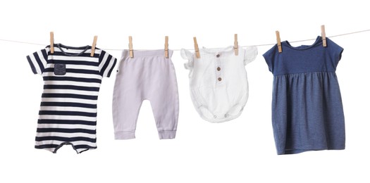 Photo of Different baby clothes drying on laundry line against white background