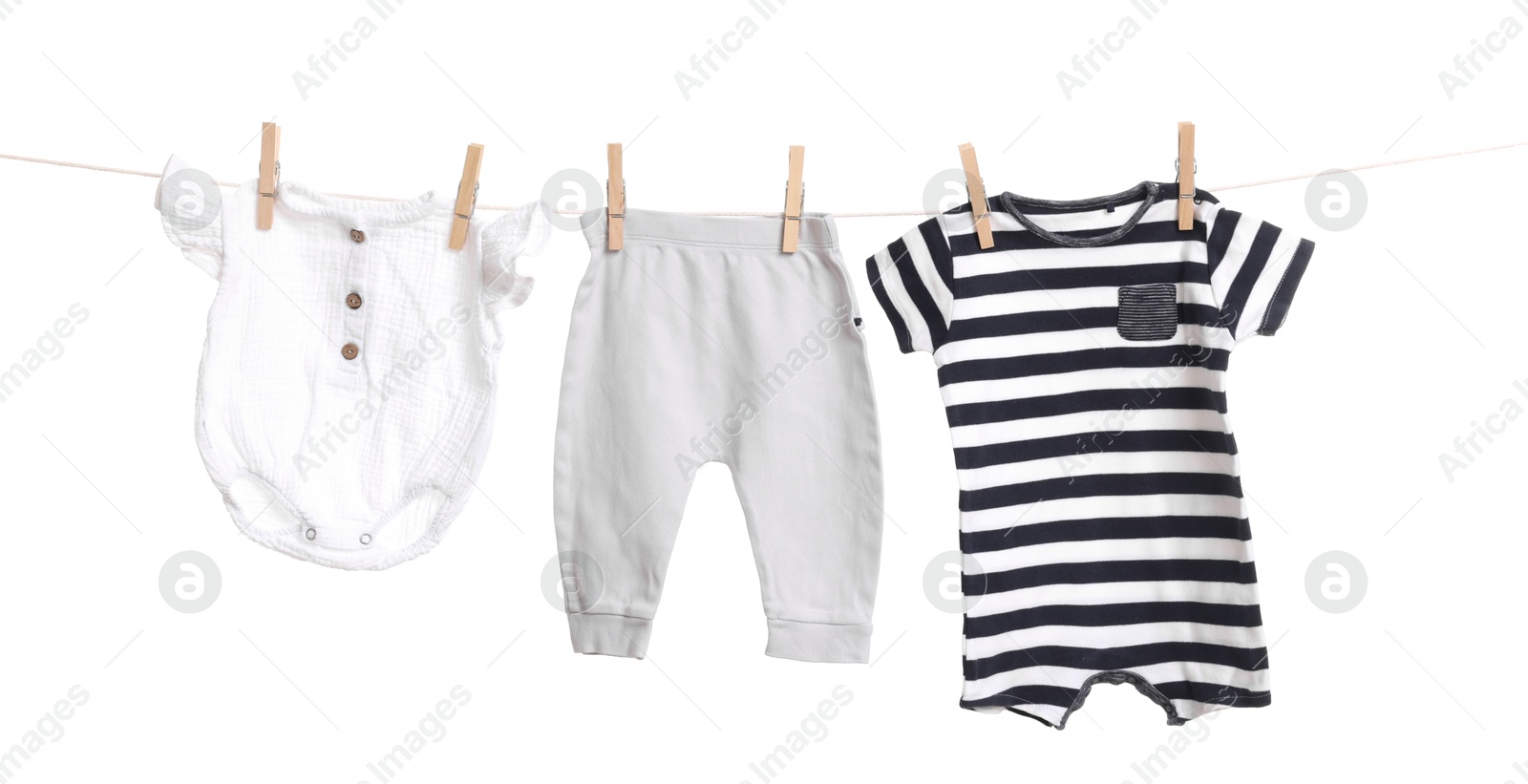 Photo of Different baby clothes drying on laundry line against white background