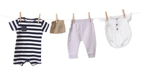 Different baby clothes drying on laundry line against white background