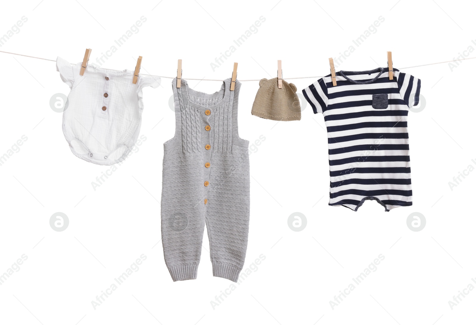 Photo of Different baby clothes drying on laundry line against white background