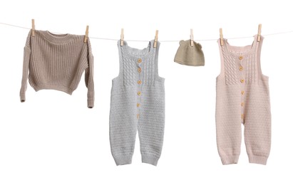 Photo of Different baby clothes drying on laundry line against white background