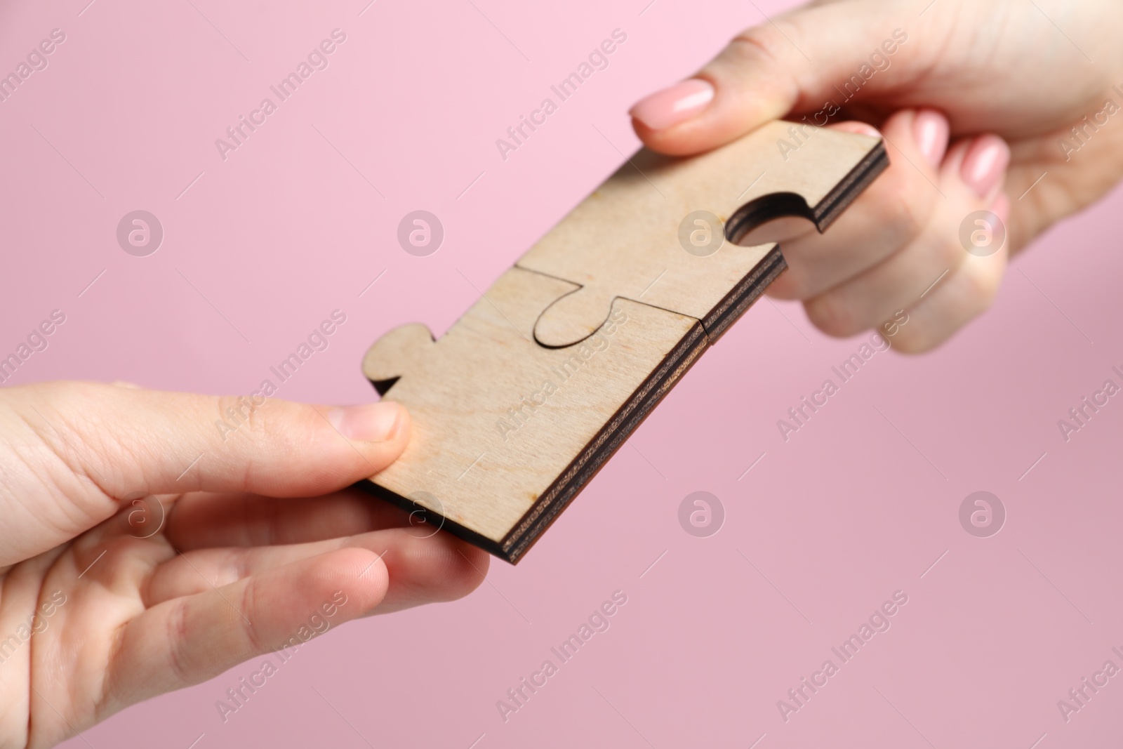 Photo of Business strategy and teamwork concept. Partners putting puzzle pieces together on pink background, closeup