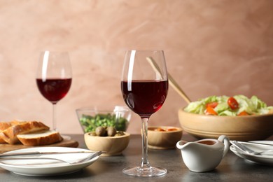 Photo of Red wine and delicious dinner served on grey table