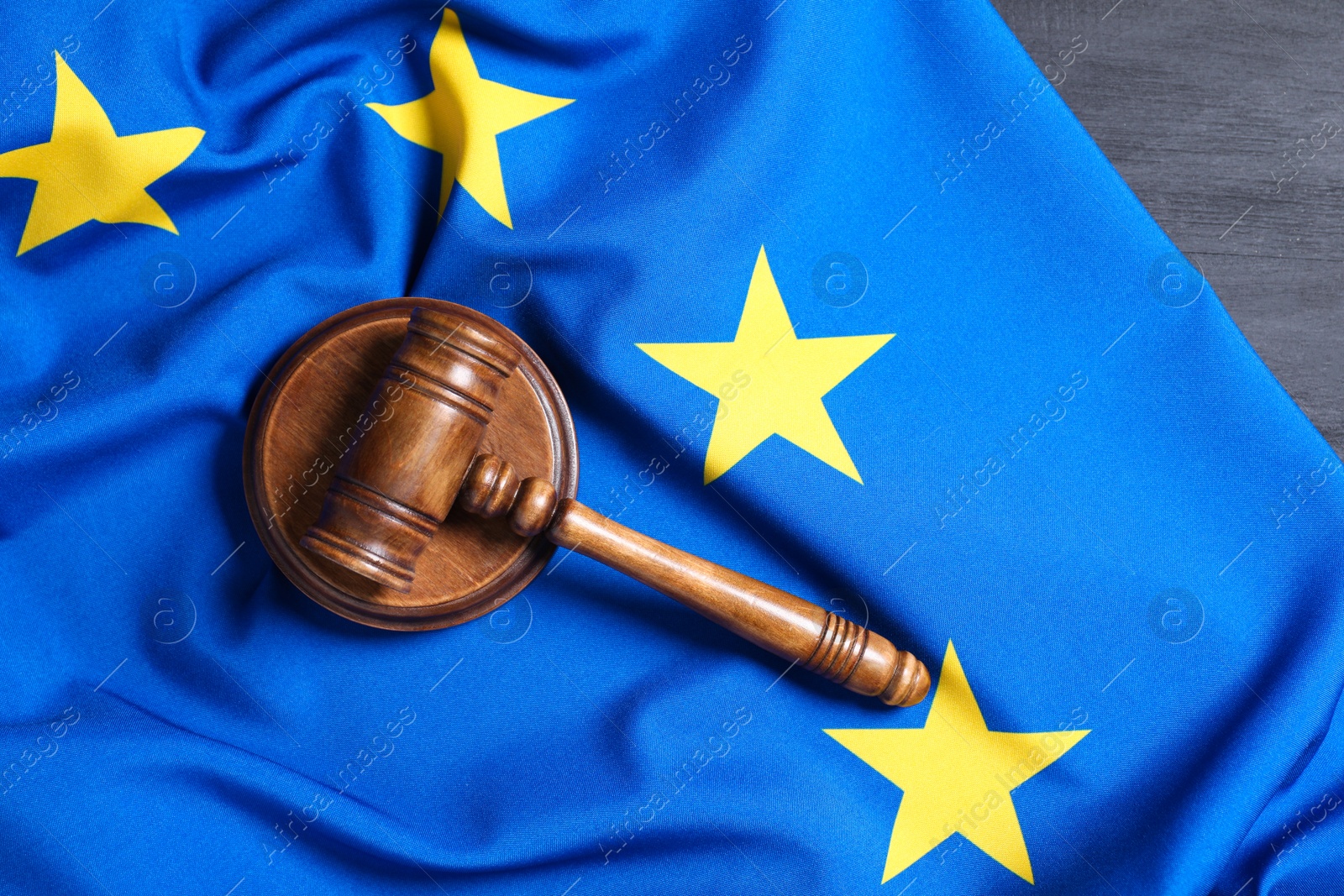 Photo of Judge's gavel and flag of European Union on grey wooden table, top view