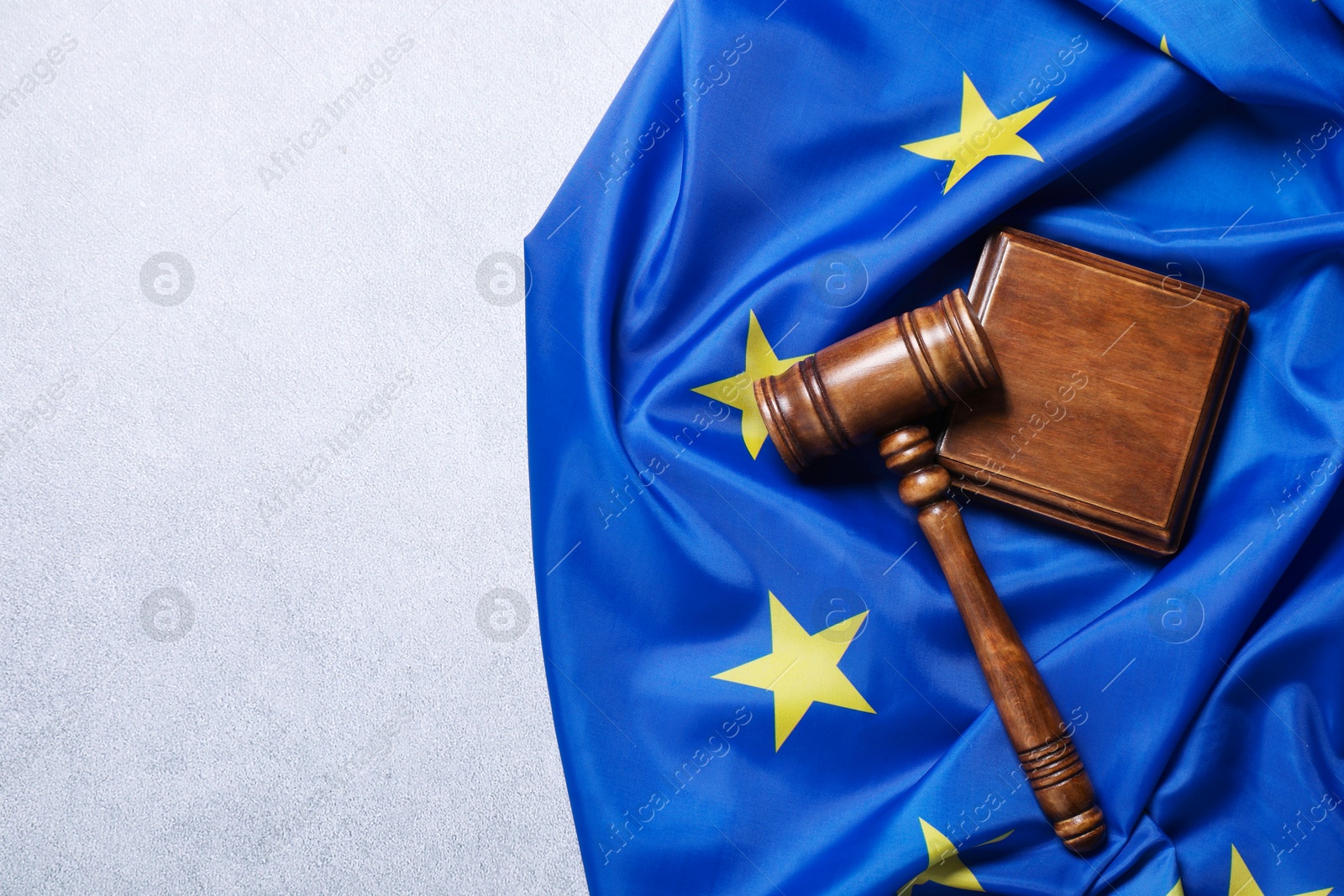 Photo of Judge's gavel and flag of European Union on light grey table, top view. Space for text