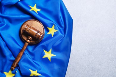 Photo of Judge's gavel and flag of European Union on light grey table, top view. Space for text