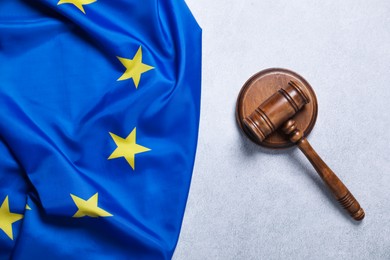 Photo of Judge's gavel and flag of European Union on light grey table, top view