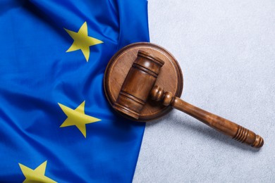 Photo of Judge's gavel and flag of European Union on light grey table, top view