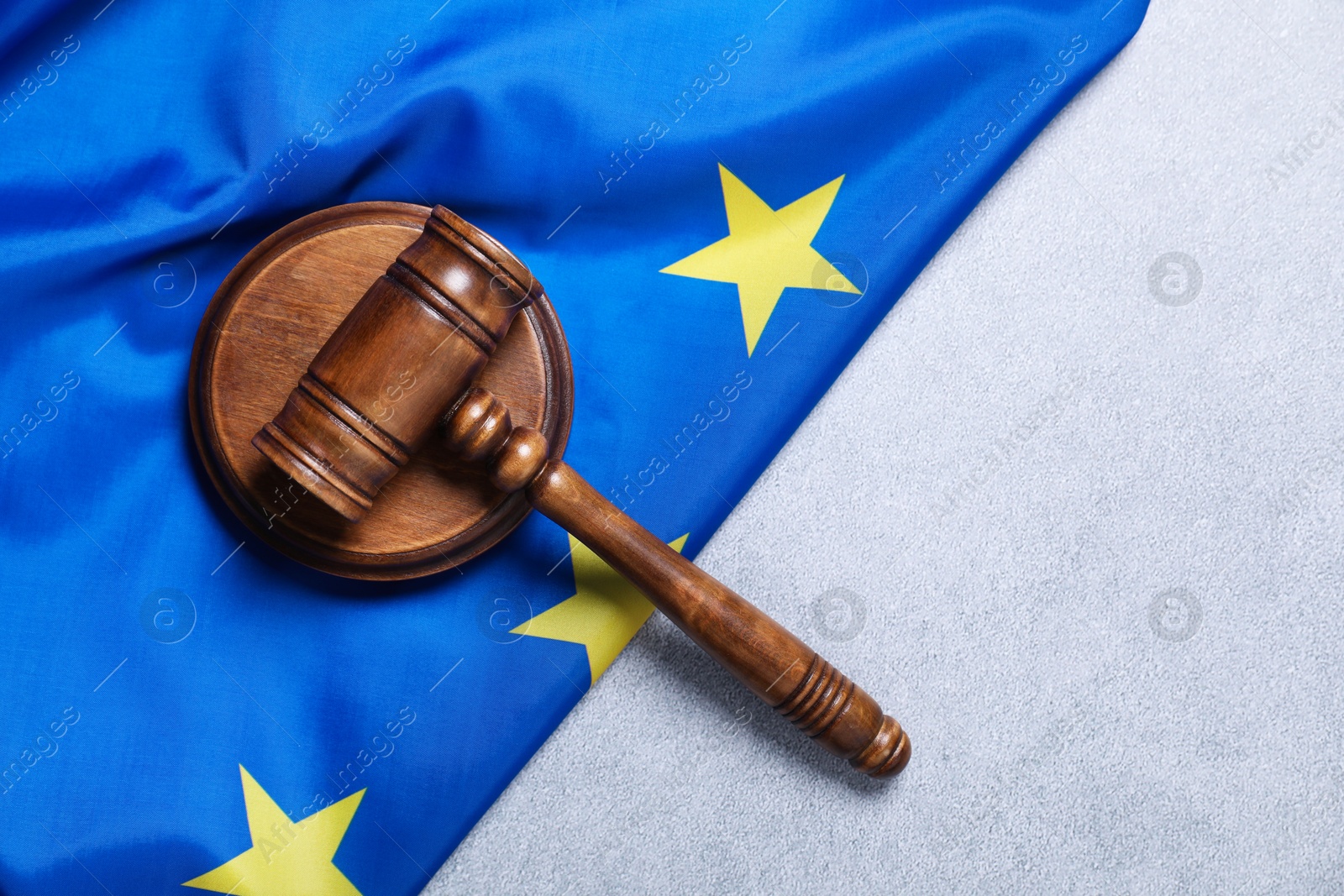 Photo of Judge's gavel and flag of European Union on light grey table, top view. Space for text