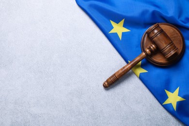 Photo of Judge's gavel and flag of European Union on light grey table, top view. Space for text