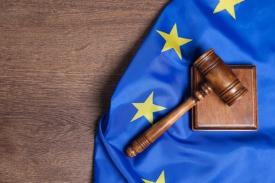 Photo of Judge's gavel and flag of European Union on wooden table, top view. Space for text