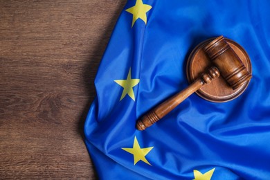 Photo of Judge's gavel and flag of European Union on wooden table, top view. Space for text