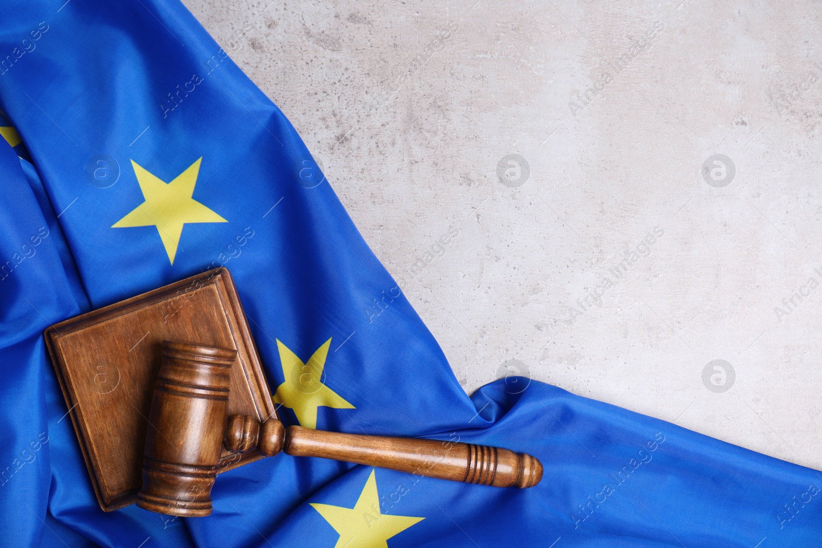 Photo of Judge's gavel and flag of European Union on grey table, top view. Space for text