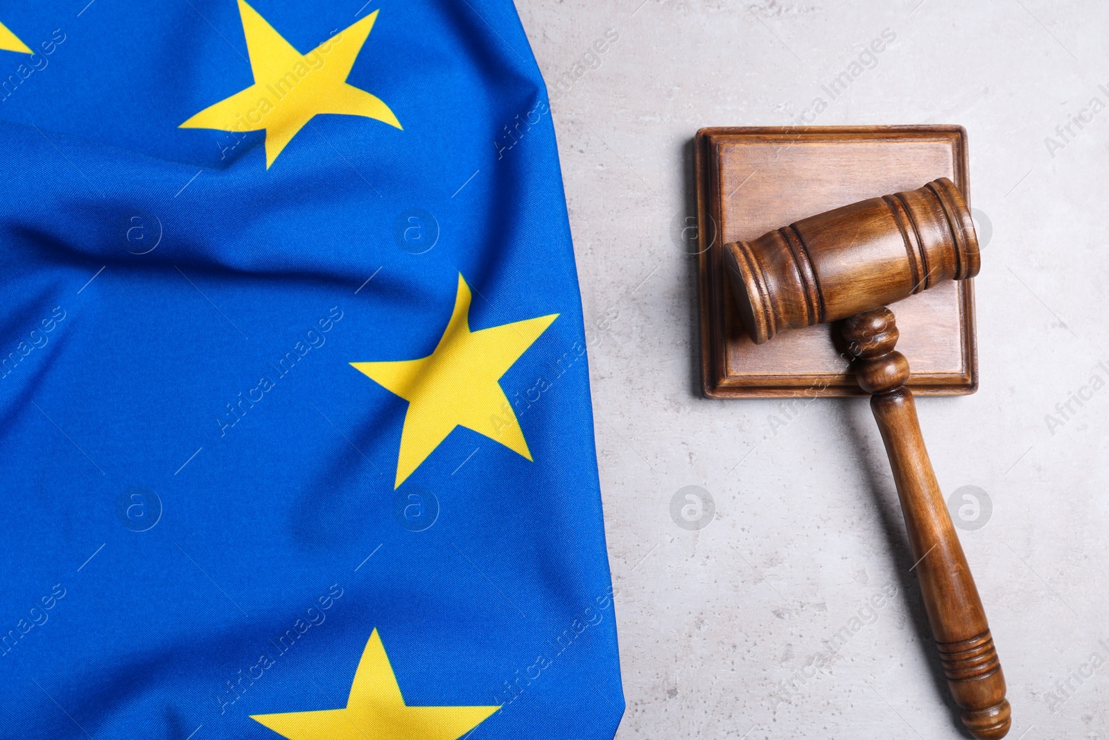 Photo of Judge's gavel and flag of European Union on grey table, top view