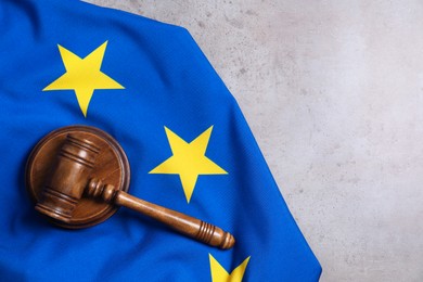 Photo of Judge's gavel and flag of European Union on grey table, top view. Space for text