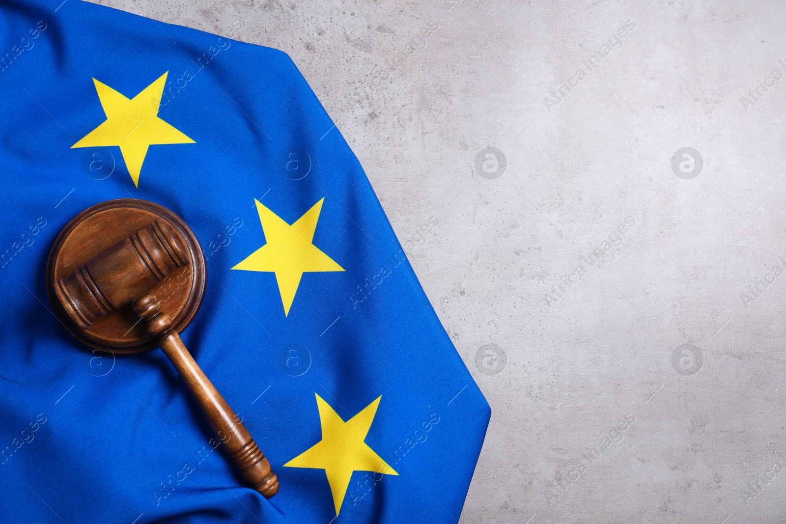 Photo of Judge's gavel and flag of European Union on grey table, top view. Space for text