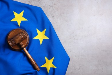 Photo of Judge's gavel and flag of European Union on grey table, top view. Space for text