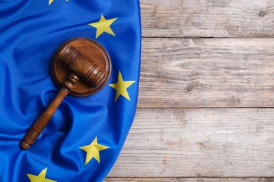 Photo of Judge's gavel and flag of European Union on wooden table, top view. Space for text