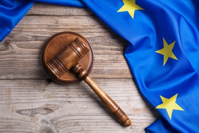 Photo of Judge's gavel and flag of European Union on wooden table, top view