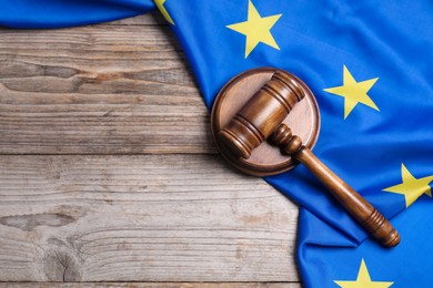 Photo of Judge's gavel and flag of European Union on wooden table, top view. Space for text