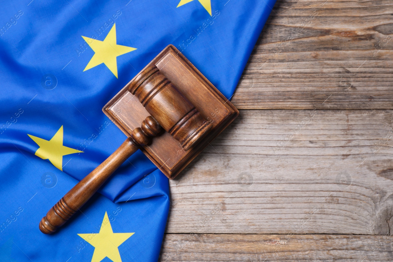 Photo of Judge's gavel and flag of European Union on wooden table, top view. Space for text