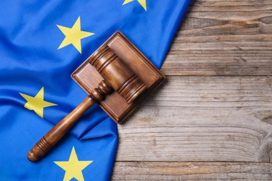 Photo of Judge's gavel and flag of European Union on wooden table, top view. Space for text