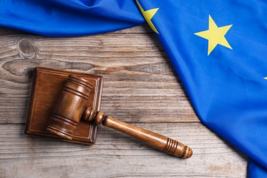 Photo of Judge's gavel and flag of European Union on wooden table, top view