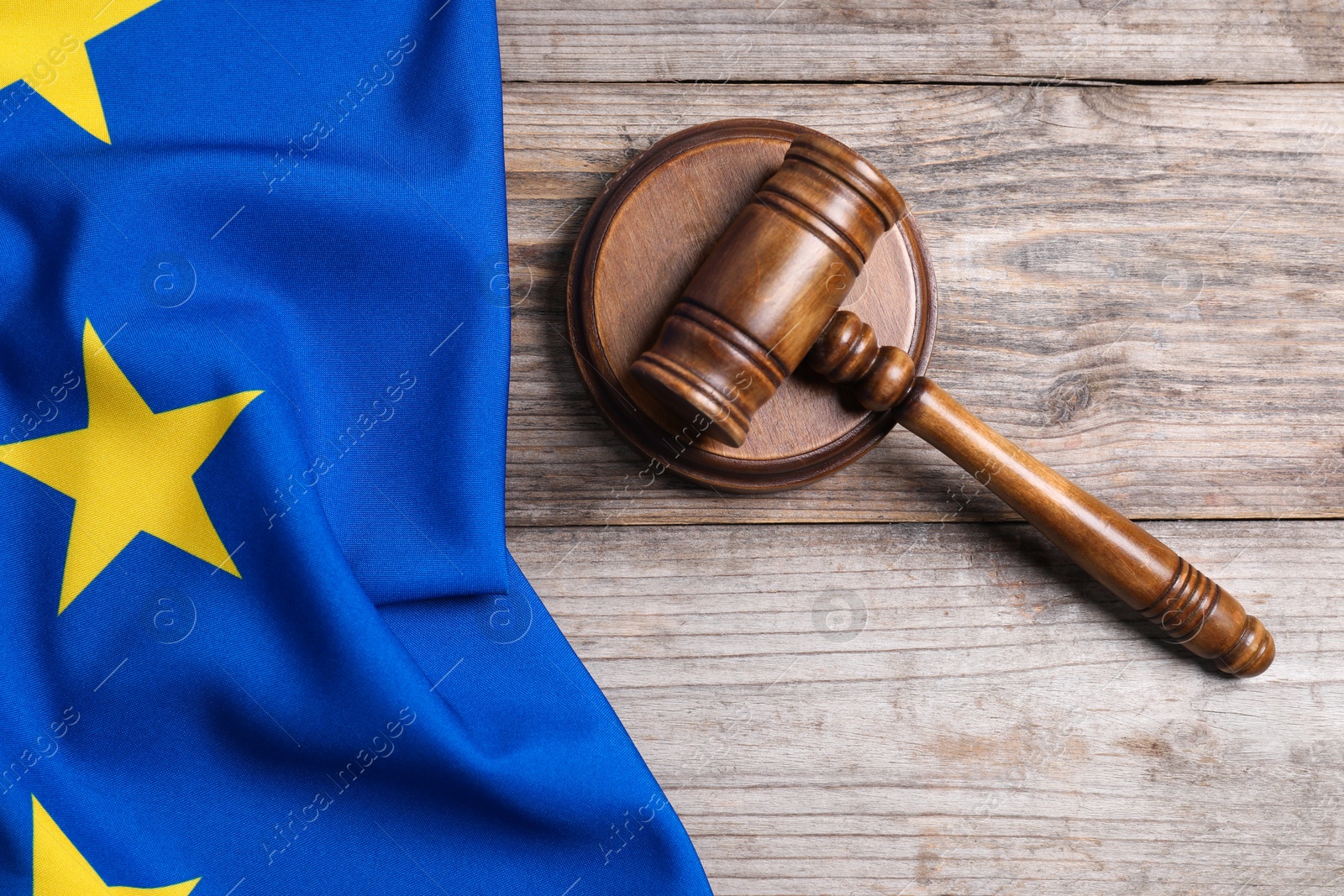 Photo of Judge's gavel and flag of European Union on wooden table, top view