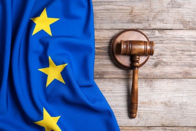 Photo of Judge's gavel and flag of European Union on wooden table, top view