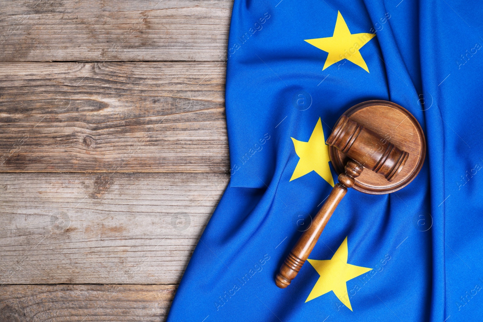 Photo of Judge's gavel and flag of European Union on wooden table, top view. Space for text