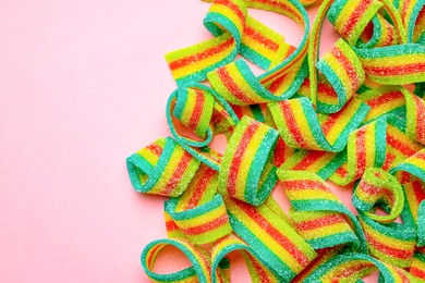 Photo of Tasty rainbow sour belts on pink background, top view. Space for text