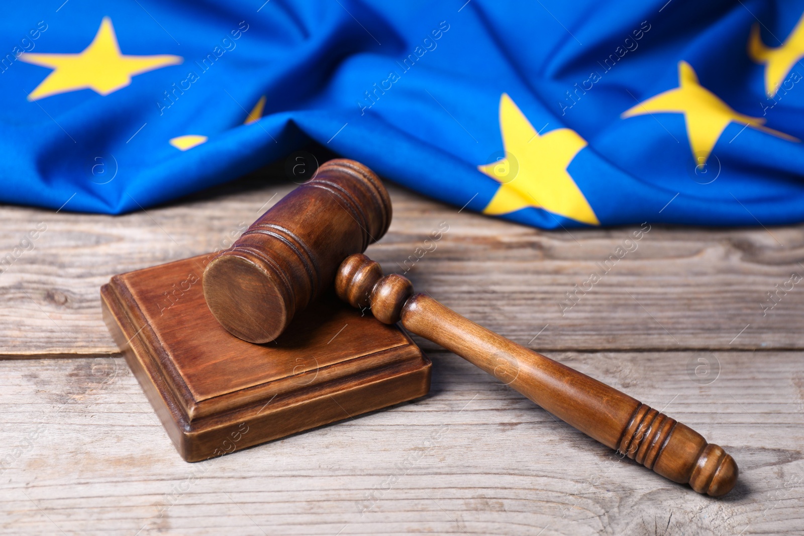 Photo of Judge's gavel and European Union flag on wooden table, closeup