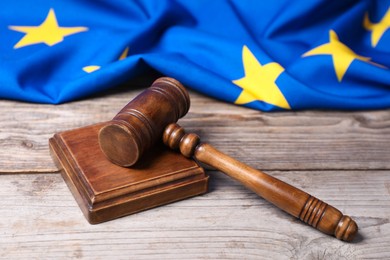 Photo of Judge's gavel and European Union flag on wooden table, closeup