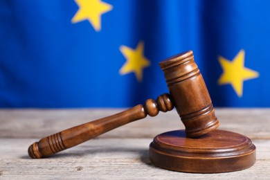 Photo of Judge's gavel on wooden table against European Union flag, closeup