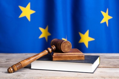 Photo of Judge's gavel and book on wooden table against European Union flag