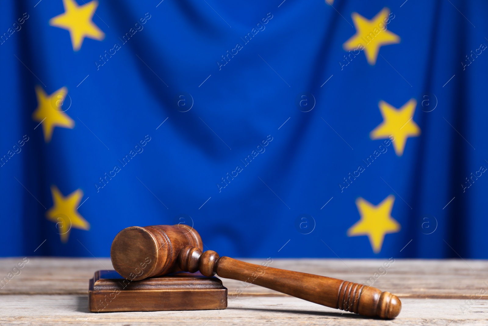 Photo of Judge's gavel on wooden table against European Union flag