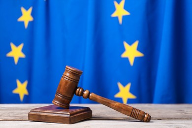 Photo of Judge's gavel on wooden table against European Union flag