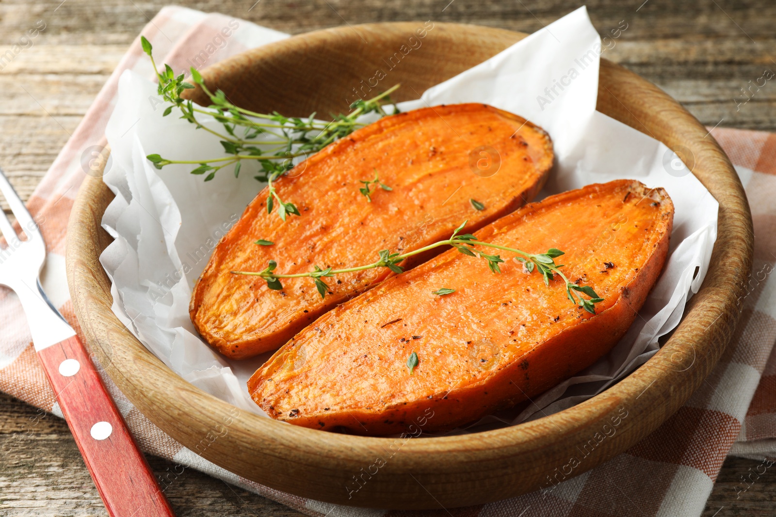 Photo of Tasty cooked sweet potato with thyme on wooden table, closeup