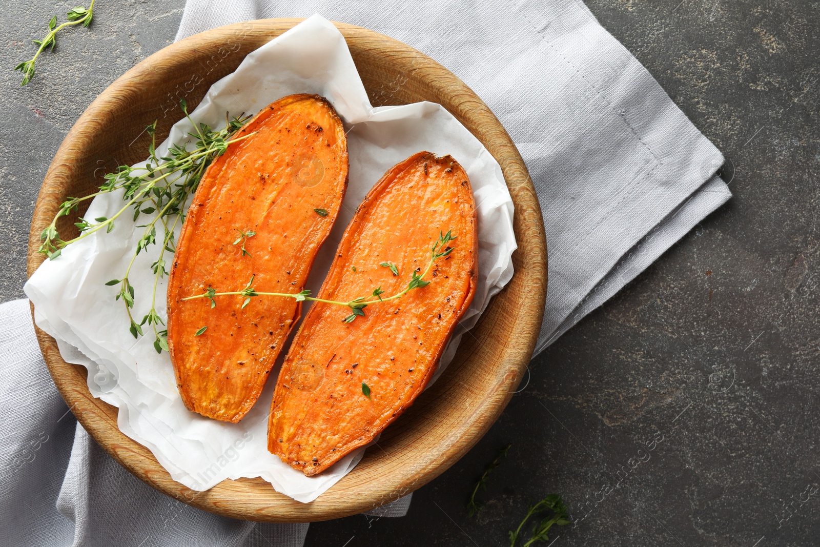 Photo of Tasty cooked sweet potato with thyme on grey table, top view