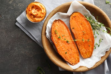 Photo of Tasty cooked sweet potato with thyme and sauce on grey table, top view