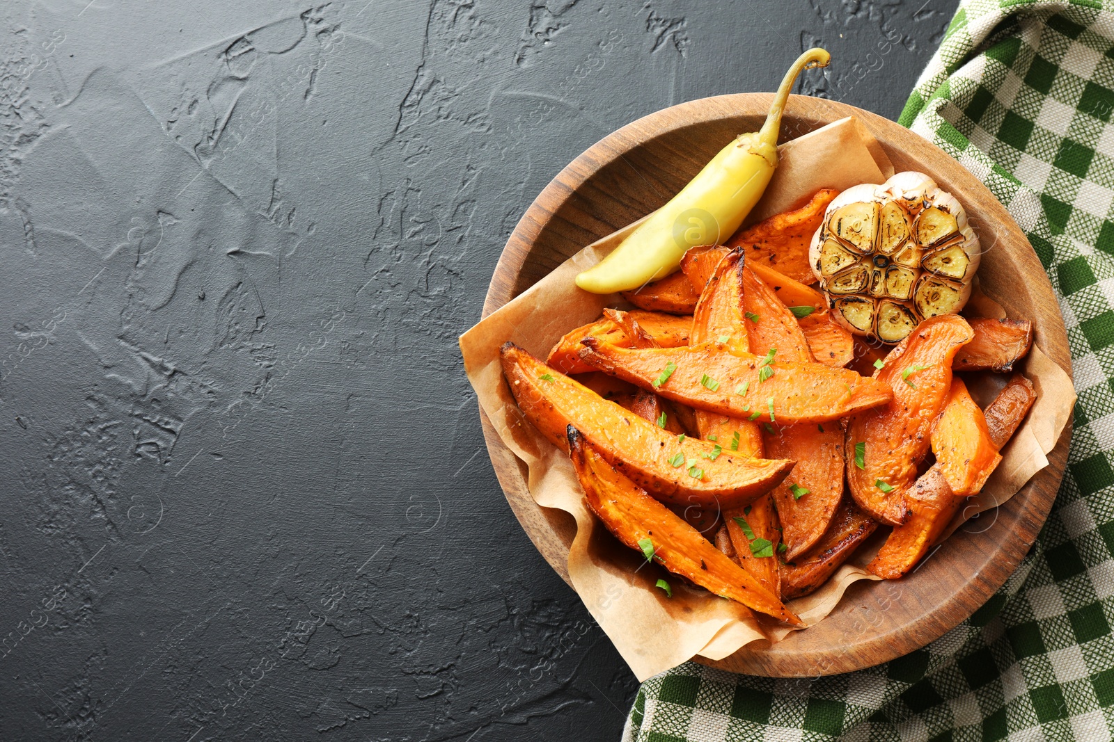 Photo of Tasty cooked sweet potatoes with garlic and pickled pepper on black table, top view. Space for text