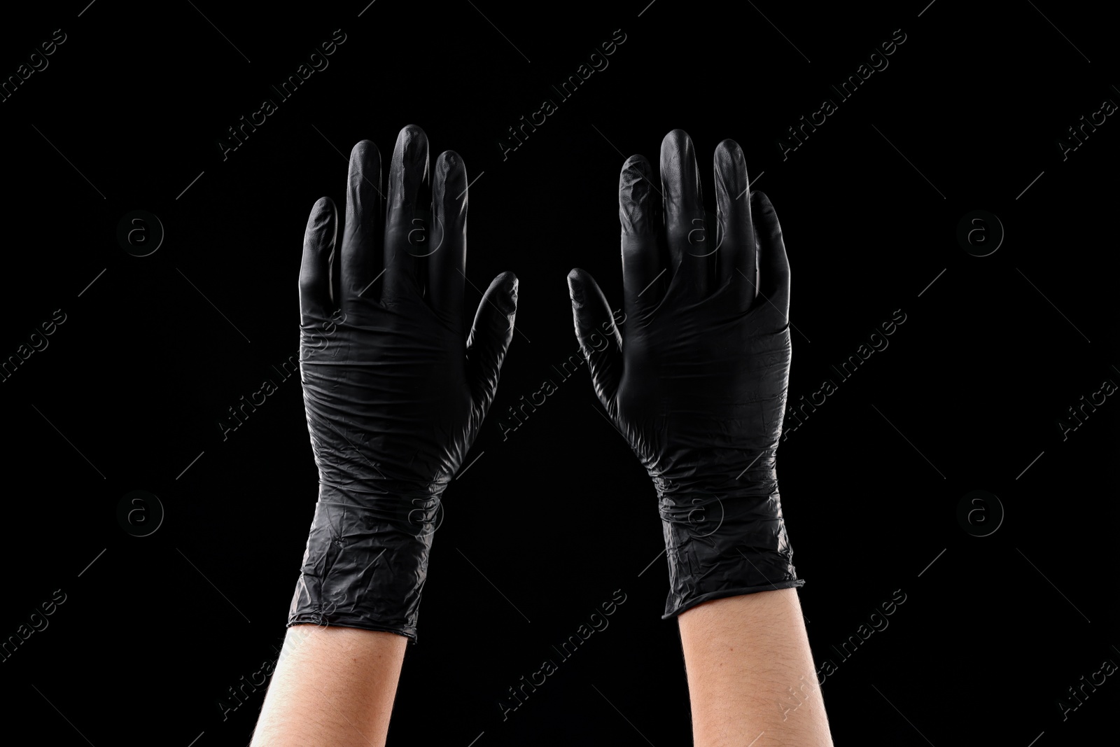 Photo of Man wearing latex gloves on black background, closeup